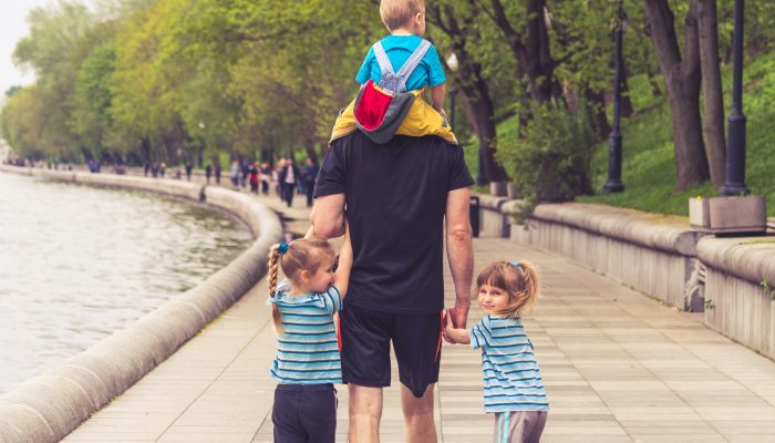 father enjoying time at park with two young daughters and young son