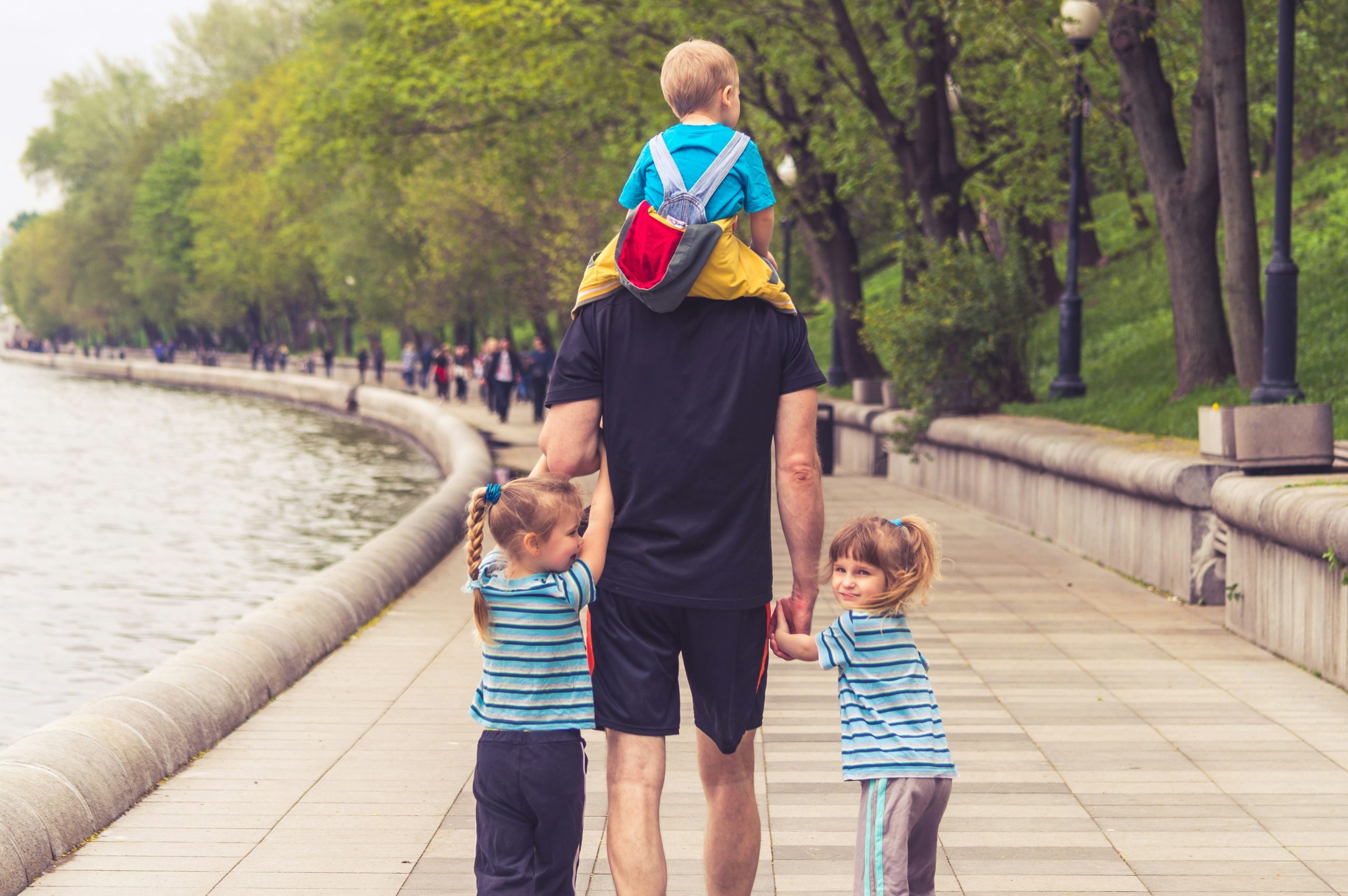 father enjoying time at park with two young daughters and young son